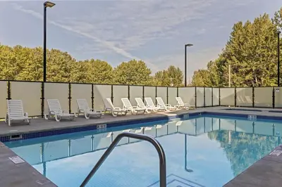 a swimming pool with lounge chairs next to a fence at 2 bedrooms-3 beds 2 baths-Rocky Creekside Retreat - Top Floor - Heated Pool and Hot Tub in Dead Man's Flats