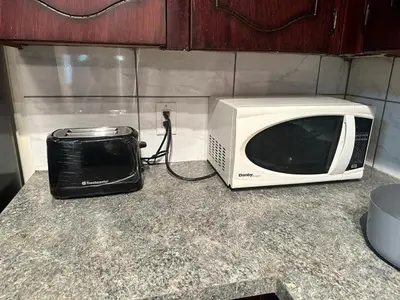 a microwave sitting on a counter next to a toaster oven at Cozy & bright private one-bed rm in Edmonton
