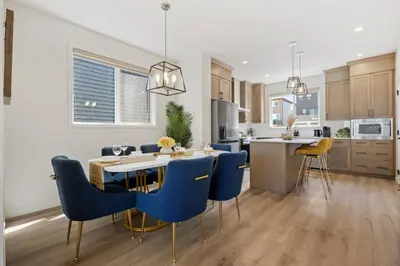 a kitchen and dining room with blue chairs and a table at 3 Bedroom Detached Home with Free Parking, Netflix, Free Banff Pass, King Size Bed & Portable AC in Balzac