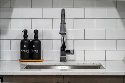 two bottles of wine sitting on a kitchen sink at Private Lower Suite, Sleeps 4, Queen Bed, Netflix, Parking in Balzac