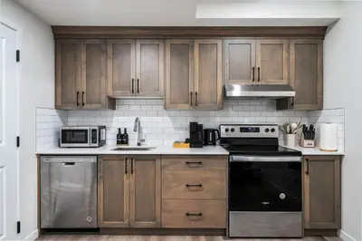 a kitchen with wooden cabinets and stainless steel appliances at Private Lower Suite, Sleeps 4, Queen Bed, Netflix, Parking in Balzac