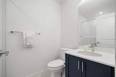 a white bathroom with a toilet and a sink at Skyline Retreat Spacious 4BR Home with Balcony! in Calgary