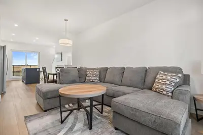 a living room with a gray couch and a table at Skyline Retreat Spacious 4BR Home with Balcony! in Calgary