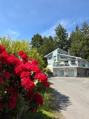 a house with red flowers in front of it at Bayview Bed and Breakfast in Mill Bay
