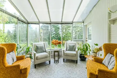 a conservatory with chairs and a table in a room with windows at Bayview Bed and Breakfast in Mill Bay