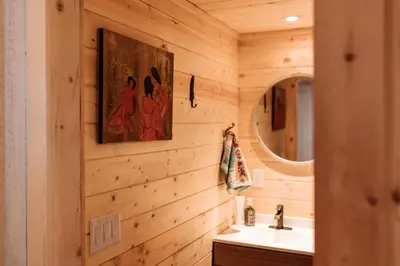 a bathroom with wooden walls and a sink and a mirror at Quiet Country Cabin in Waiparous Village