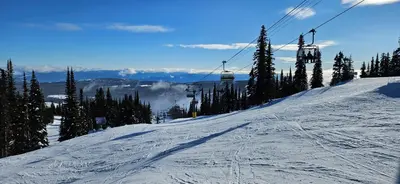 a snow covered ski slope with a ski lift at The Marmot's Den in Sun Peaks