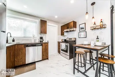 a kitchen with wooden cabinets and a table with bar stools at Park Life Escape-King Beds-Sleeps 10-Pet Friendly in Edmonton