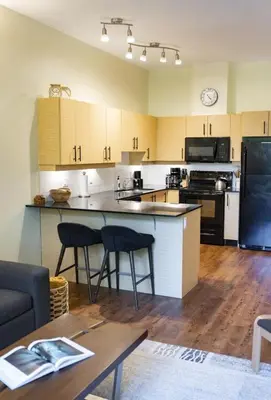 a kitchen with a counter and two bar stools at Surfers' Nest - Waterfront home in Ucluelet in Ucluelet