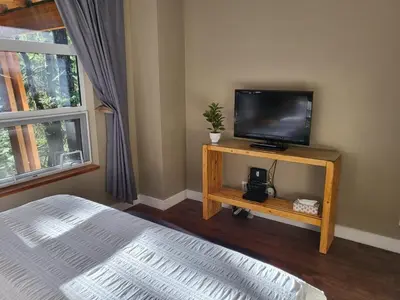 a bedroom with a tv on a table with a bed at Surfers' Nest - Waterfront home in Ucluelet in Ucluelet