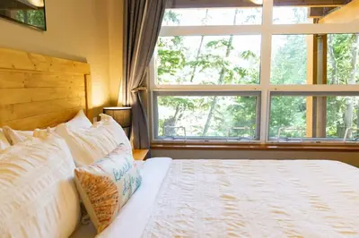a bedroom with a bed with a large window at Surfers' Nest - Waterfront home in Ucluelet in Ucluelet