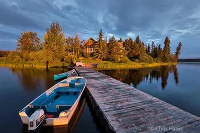 a boat docked at a dock in front of a house at Eagle's Nest Resort in Anahim Lake