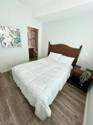 a bedroom with a white bed with a wooden floor at Sandy beach Sauvignon cottage - Osoyoos escapade 3bd-2bt in Osoyoos