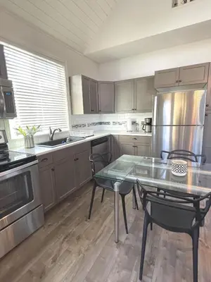 a kitchen with a table and a stainless steel refrigerator at Sandy beach Sauvignon cottage - Osoyoos escapade 3bd-2bt in Osoyoos