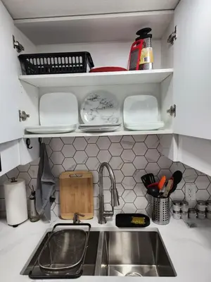 a kitchen counter with a sink and dishes on shelves at Super luxury suite in Edmonton