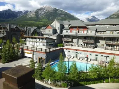 a resort with a pool and mountains in the background at Mountain Memories Family Fun at The Lodges in Canmore