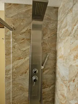 a shower in a bathroom with a stone wall at Falcon Crest Canmore Banff in Canmore