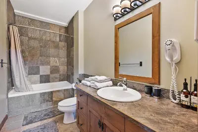 a bathroom with a sink and a toilet and a mirror at Snow Therapy Chalet - Ski In Out, Hot Tub & Mtn View in Big White