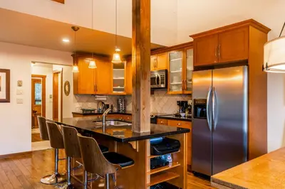 a kitchen with wooden cabinets and a stainless steel refrigerator at Best Location Available in Whistler Village in Whistler