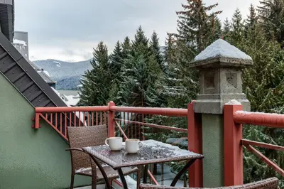 a table on a balcony with two mugs on it at Village Penthouse w Views Pool and Hot Tub in Whistler