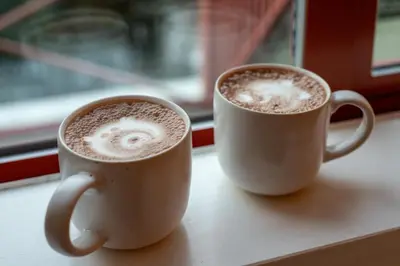 two cups of coffee sitting on a window sill at Village Penthouse w Views Pool and Hot Tub in Whistler