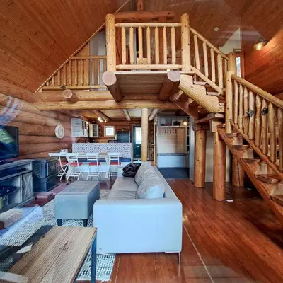 a living room with a staircase in a log cabin at Eagle Nest by StayIn in Fairmont Hot Springs