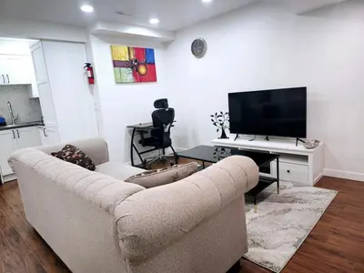 a living room with a couch and a flat screen tv at Cozy & Spacious 1-Bedroom SW Calgary near SpruceMeadows in Calgary
