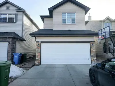 a house with a white garage door in a driveway at Cozy & Spacious 1-Bedroom SW Calgary near SpruceMeadows in Calgary