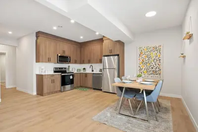 a kitchen with wooden cabinets and a table with chairs at 2 Bedroom Spacious & Private Guest Suite - King Size Bed TV in Room, 58