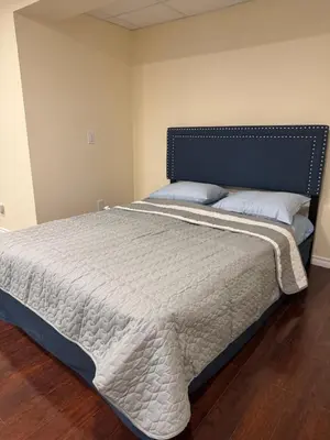 a bedroom with a large bed with a blue headboard at Home Away from Home in Calgary