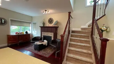 a living room with a staircase with a chair and a fireplace at Spacious 6 beds 3 baths home in Central WiFi parking AC in Edmonton