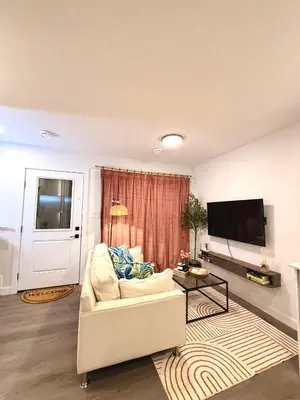a living room with a white couch and a flat screen tv at 2bed Lagos House Backyard Suites Downtown in Edmonton