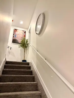 a stairway with a clock on the wall and a plant at 2bed Lagos House Backyard Suites Downtown in Edmonton