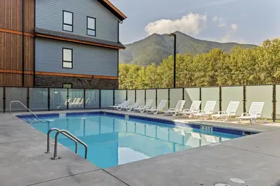 a swimming pool with chairs and a house at 2 bedrooms-3 beds 2 baths - Rocky Mountain View Retreat - Heated Pool and Hot Tub in Dead Man's Flats