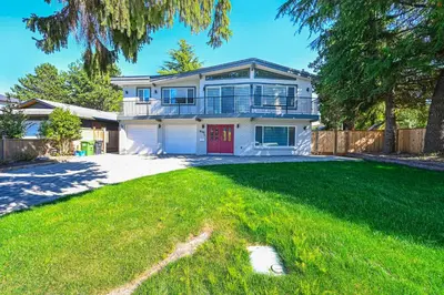 a white house with a red door and a yard at Cozy Home with 3BR 4Bath near Richmond Steveston Village in Richmond