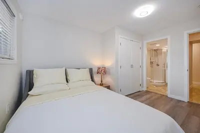 a bedroom with a large white bed and a bathroom at Cozy Home with 3BR 4Bath near Richmond Steveston Village in Richmond