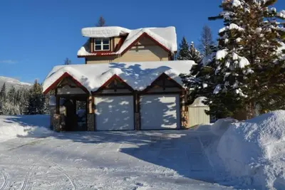 a house with a garage covered in snow at Stemwinder Duplex Chalet by StayIn in Kimberley