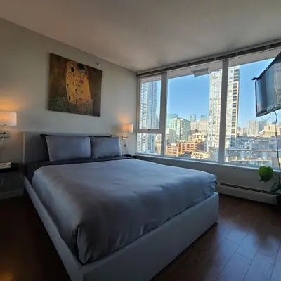 a bedroom with a large bed with a large window at Charming Abode Downtown Vancouver in Vancouver