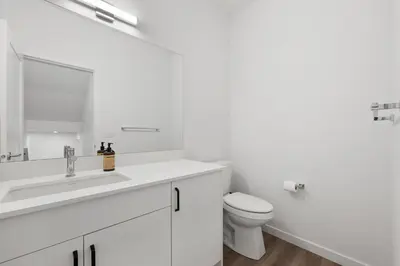 a white bathroom with a sink and a toilet at Luxury 3 Bedrooms Spacious Townhome, 2 Car Garage, Sleeps 8, Heater & AC, King Bed, Easy Ski Access, Next to WinSport, 10km from Calgary Downtown, Near Banff in Calgary