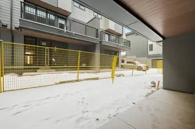 a fence in the snow in front of a building at Luxury 3 Bedrooms Spacious Townhome, 2 Car Garage, Sleeps 8, Heater & AC, King Bed, Easy Ski Access, Next to WinSport, 10km from Calgary Downtown, Near Banff in Calgary