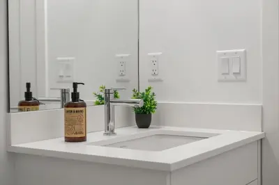 a white bathroom sink with a bottle of soap on it at Luxury 3 Bedrooms Spacious Townhome, 2 Car Garage, Sleeps 8, Heater & AC, King Bed, Easy Ski Access, Next to WinSport, 10km from Calgary Downtown, Near Banff in Calgary