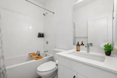 a white bathroom with a toilet and a sink at Luxury 3 Bedrooms Spacious Townhome, 2 Car Garage, Sleeps 8, Heater & AC, King Bed, Easy Ski Access, Next to WinSport, 10km from Calgary Downtown, Near Banff in Calgary