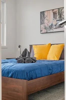 a bed with blue sheets and yellow pillows at Luxury 3 Bedrooms Spacious Townhome, 2 Car Garage, Sleeps 8, Heater & AC, King Bed, Easy Ski Access, Next to WinSport, 10km from Calgary Downtown, Near Banff in Calgary