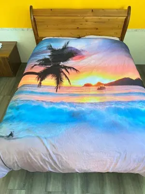 a bed with a painting of a beach with a palm tree at Surrey central house in Surrey