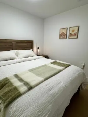 a bedroom with a large bed with a green and white blanket at Levida Living - Cozy 2 Bedroom Suite at the Heart of Langley in Langley