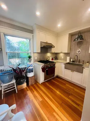 a kitchen with white cabinets and a wooden floor at 3 level, home near downtown! in Vancouver