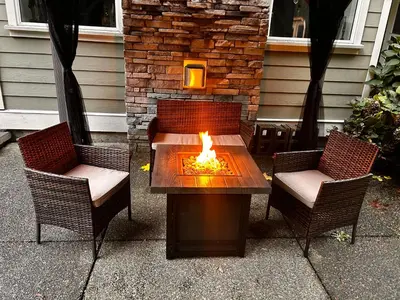 a patio with two chairs and a table with a fire pit at Charming scape by Bear Mountain in Victoria