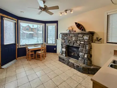 a living room with a stone fireplace and a table at Pika's Place Bed and Breakfast in Canmore