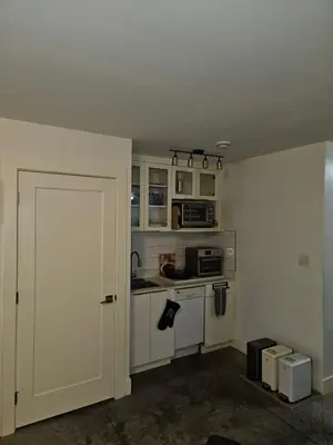 an empty kitchen with white cabinets and a door at The Ridge in North Vancouver