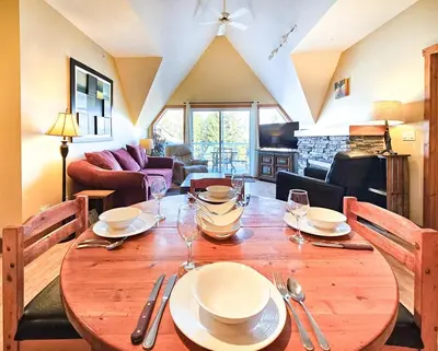 a wooden table with plates and wine glasses on it at Heron Point by StayIn in Invermere